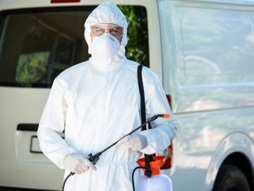 Technicien nuisibles en tenue de protection intervention extérieure traitement anti nuisibles